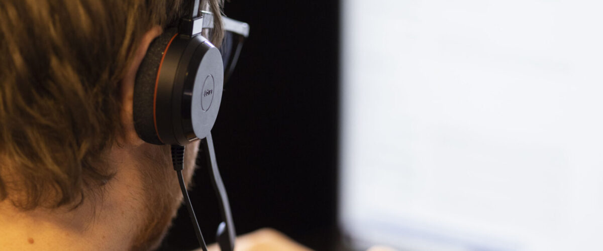 Foto av telefonselger i Nexctcall, mann som ringer i headset foran PC.